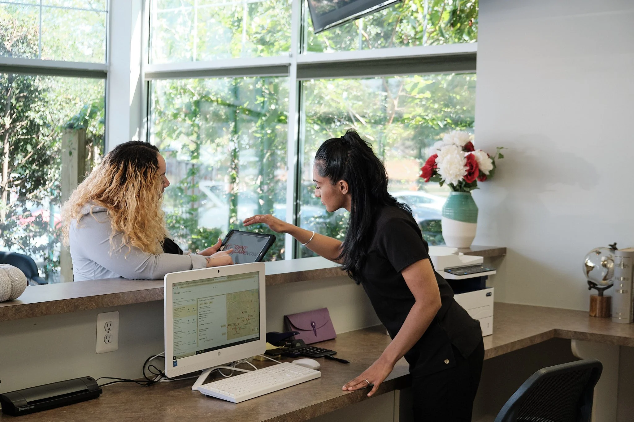 Team member at front desk checking in a patient at Dentcare Now's reception area
